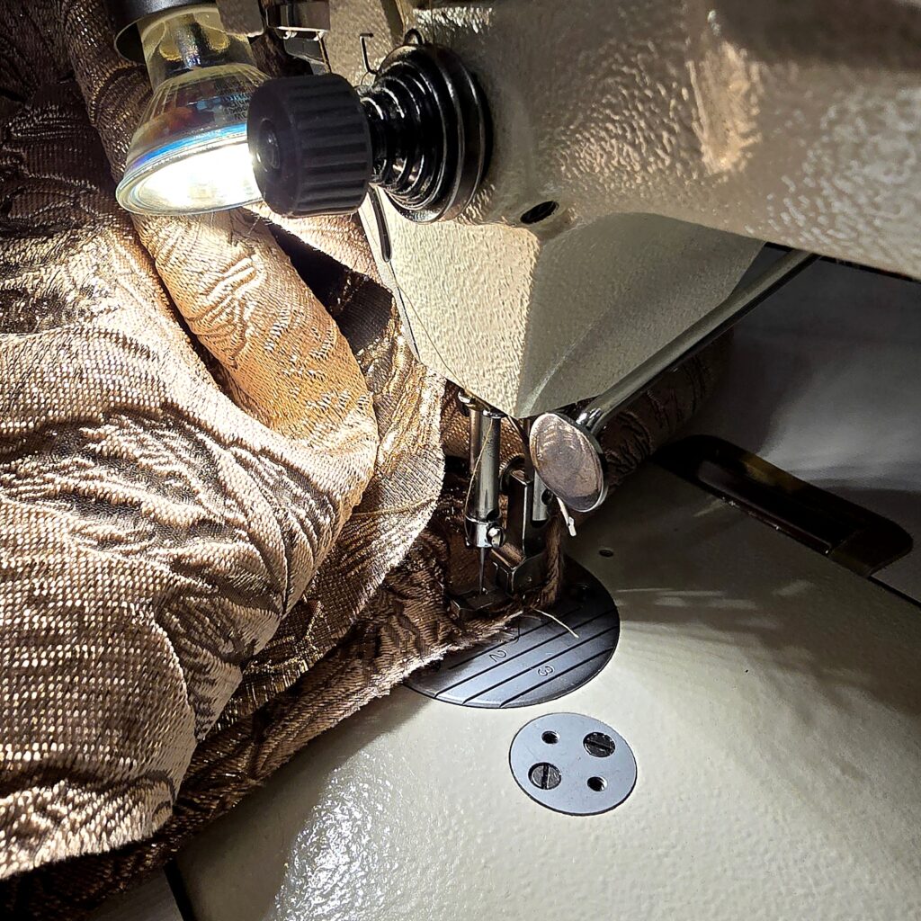 Nähmaschine bei der Verarbeitung eines feinen Stoffes im Atelier für individuelle Kleidungsstücke