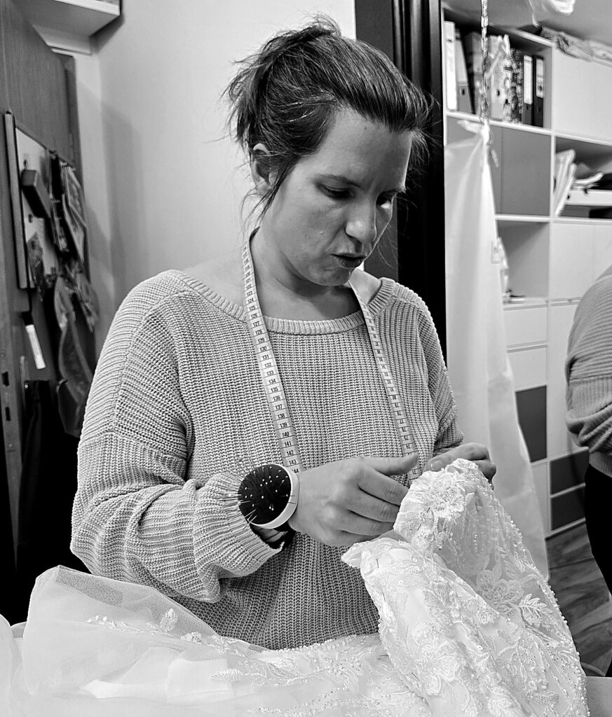 Schneiderin arbeitet im Atelier an einem feinen Kleidungsstück mit Maßband und Handarbeit